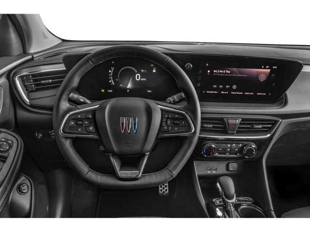 close up view of 2025 Buick Encore GX front dashboard from the drivers point of view. Steering wheel, temperature controls, gear shift and touch screen are visible.