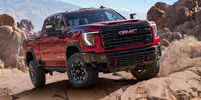 2025 GMC Sierra HD driving on a rocky desert road